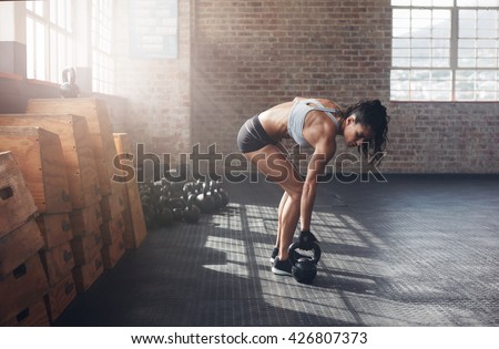 Full length shot of fitness woman doing exercising with kettle bell. Determined female model about to start her fitness regime at the  gym.