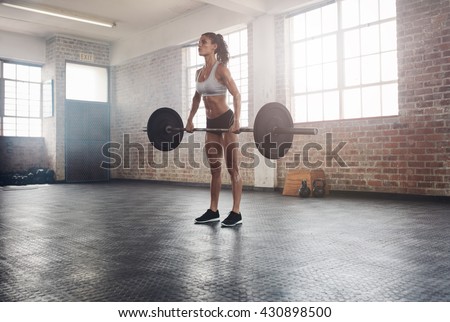 Fitness woman preparing to practice deadlift with heavy weights in gym. Female doing heavy weight lifting work out in health club.