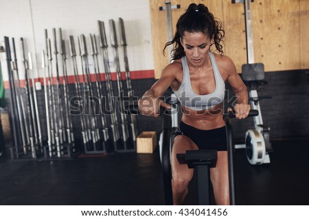 Fitness woman on bicycle doing spinning at gym. Fit young female working out on gym bike.