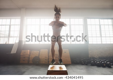Shot of young woman working out with a box at the gym. Young female athlete box jumping at a crossfit gym.