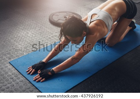 Young woman doing stretching exercises in a health club. Woman on fitness mat doing stretching workout at gym.