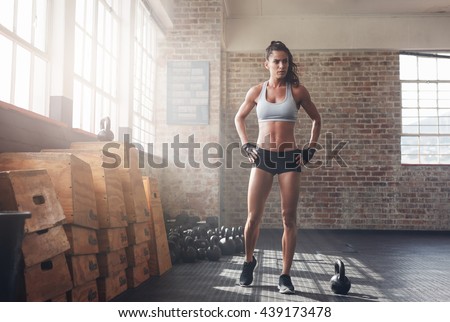 Full length shot of determined fitness woman walking in the crossfit gym. Muscular sportswoman warming up before a intense workout.