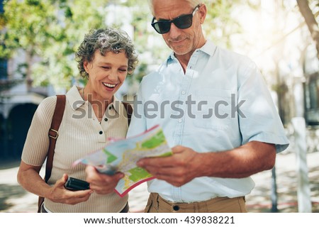 Senior couple on vacation reading a map. Mature man and woman looking for direction in foreign city.