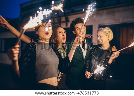 Group of friends enjoying out with sparklers on city street. Young people enjoying new years eve with fireworks.