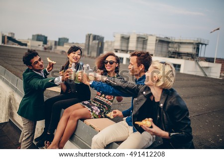 Diverse group of young friends on terrace party. Young men and women having drinks on rooftop party.