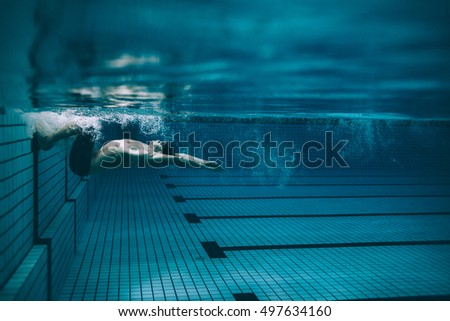 Underwater shot of male swimmer turning over in swimming pool. Pro male swimmer in action inside pool.