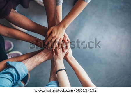 Close up top view of young people putting their hands together. Friends with stack of hands showing unity and teamwork.