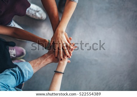 Cropped image of young people\'s hands on top of each other. Top view of young group with hands on stack.