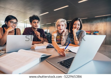 College students using laptop while sitting at table. Group study for school assignment.