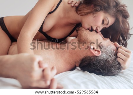 Young couple being intimate kissing on bed. Sensual lovers making love in bedroom.