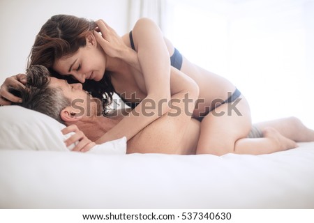 Intimate lovers making love in bed. Romantic and passionate young couple on bed.
