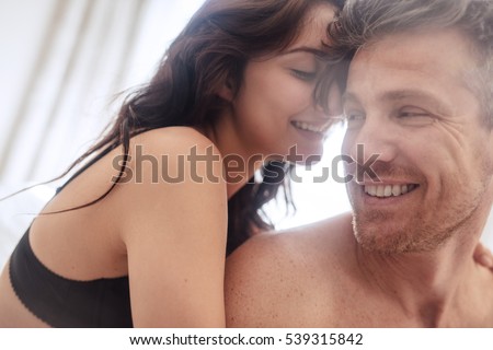 Sensual young couple together in bed. Happy couple in bedroom enjoying sensual foreplay.