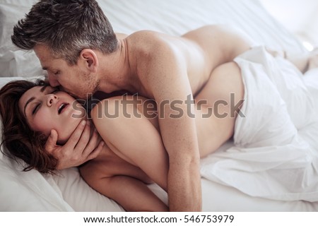 Sensual young couple making love in bedroom. Romantic man and woman having intimate sex in bed