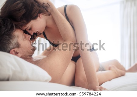 Young beautiful sexy woman lying on her man while having sex. Passionate couple making love on bed.