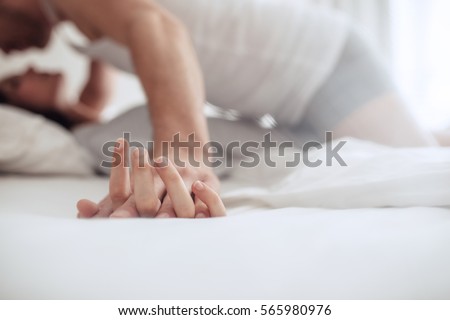 Romantic couple in bed enjoying sensual foreplay. Focus on hands man and woman.