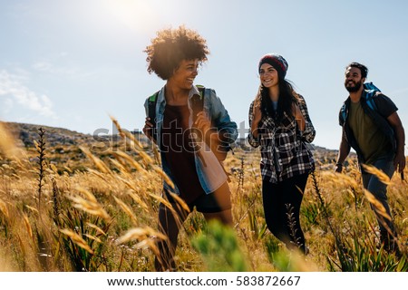 Happy group of friends hiking together on a summer day. Group of friends on walk through countryside.