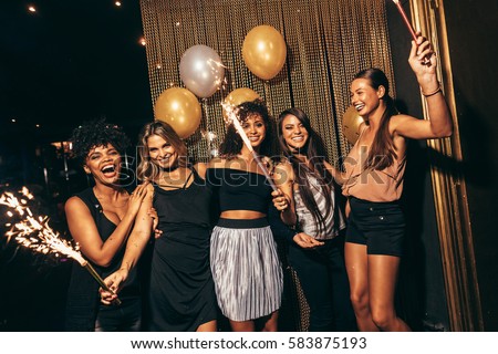 Group of women with fireworks at party. Stylish girls enjoying party at nightclub.