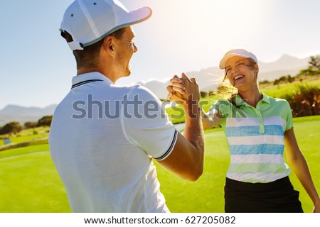 Happy male and female friends shaking hands at golf course after the game. Pro golfer enjoying the game on field.