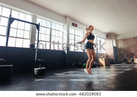 Young woman exercising using skipping rope in gym. Athletic woman training hard at the gym.