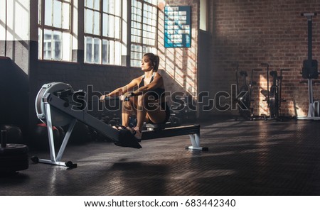 Woman doing muscle training at the gym. Athlete working out at the gym by pulling weight.