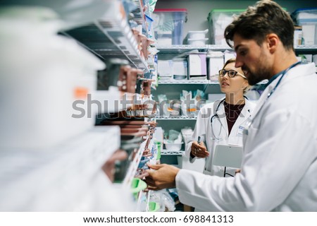 Two pharmacist working in drugstore. Male and female pharmacists checking medicines inventory at hospital pharmacy.