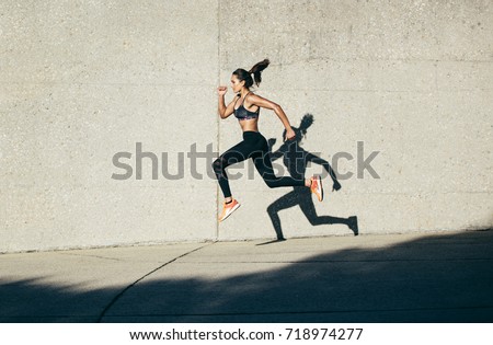 Strong woman in sportswear running and exercising outdoors. Caucasian female doing running workout in morning.