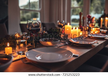 Close up shot of christmas festive table with no people. Dining table with plates, wine glasses and candles.
