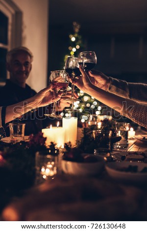 Close up shot of family toasting wine at christmas dinner. Family enjoying christmas dinner together at home, with focus on hands and wine glasses.