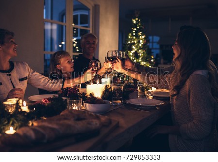 Family toasting with wine in a christmas dinner at home in the living room. Happy family celebrating christmas together at home.