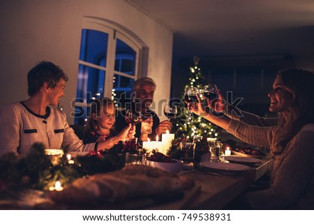 Three generation family enjoying christmas dinner together at home. Extended family toasting wine at christmas dinner.