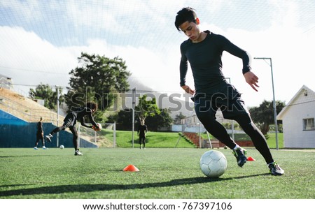 Football player training in soccer field. Young soccer player practicing ball control on training session.