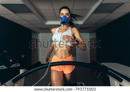 VO2 max test. Sportswoman with mask running on treadmill. Female athlete in sports science lab measuring her VO2 max.