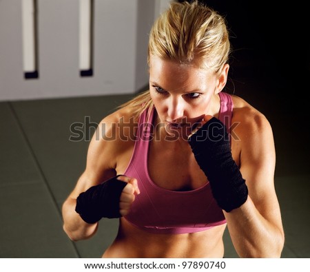 Blonde woman doing martial arts workout in a gym