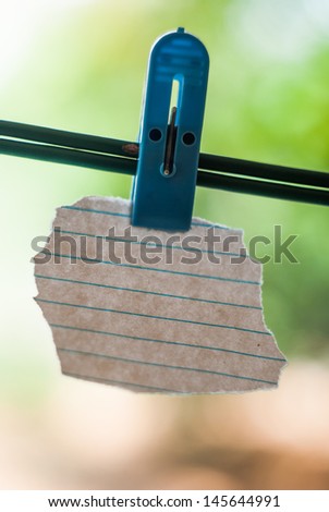 white lined random shape note paper hanging from a support with help of a clip