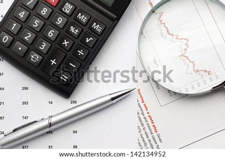 Business concept. Close up of Calculator, pen near magnifying glass and business paper