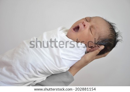 Newborn baby boy yawning held in mom's hands