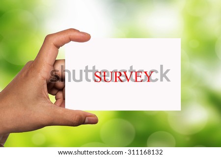 hand holding white card written survey over blur background