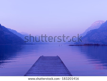 Evening on the lake in Switzerland. Water and mountains painted in pink and purple colors