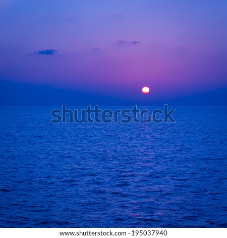 Spectacular sunset. Setting sun painted the sky, clouds and ocean in Deep blue color.