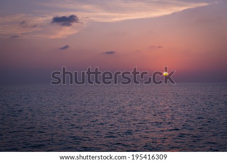 Sunset over the sea. Rays of the sun through the clouds. Setting sun painted the sky  in bright color.