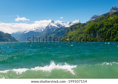 Lake in central Switzerland,  canton  Schwyz. Wave splash and spray. Alps in the snow. Bright blue, green colors.