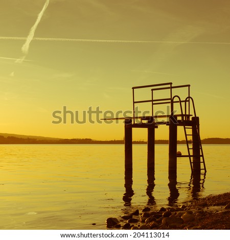 Gorgeous evening sunset colors in the sky and the lake. Lake Zug in central Switzerland. High-board in water.