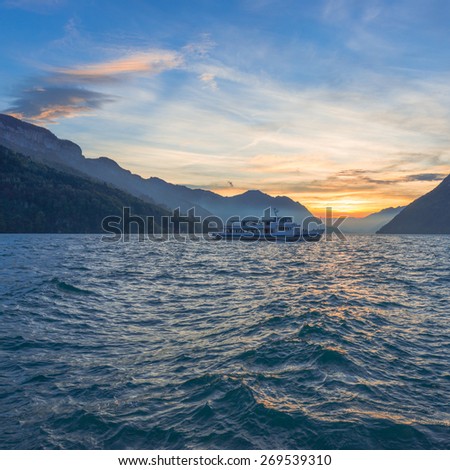 Evening in Switzerland. Boat trip on the lake. Sunset on the lake on a windy day. Many clouds in the sky. The play of light and shadow in the mountains