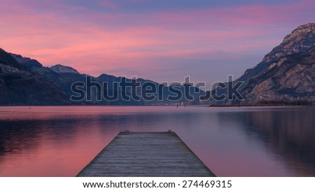 Spectacular sunset over lake in mountains. Gorgeous colors of clouds reflected in water. Long exposure