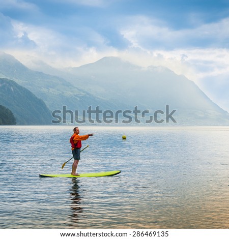 Brunnen, Switzerland -June 11, 2013. One man stand up padling on the lake with outstretched arm points.