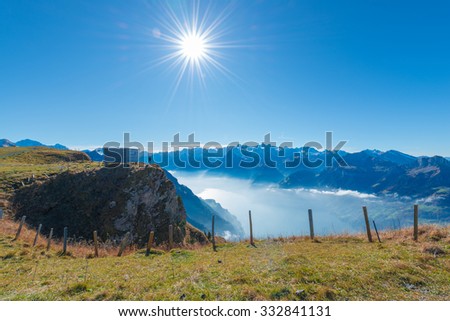Epic landscape with a small figure of human. Aerial view of the top of mountains down to the lake in fog and clouds.