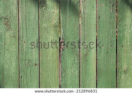green wooden old fence boards of different widths, worn from time to time