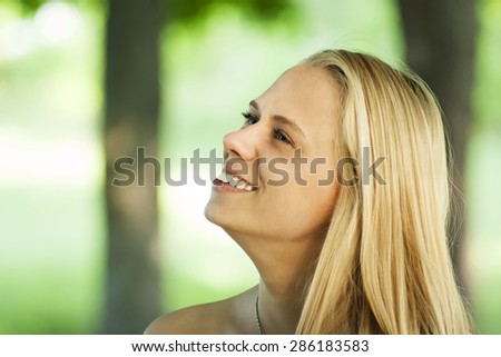 young and beautiful girl withblue eyes smile and posing in the green and trees in the summer