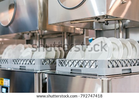 close up white plate on basket in automatic dishwasher machine for industrial