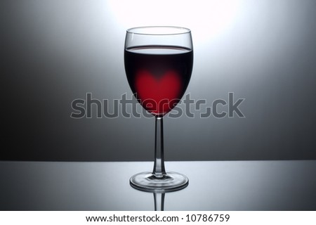 A back-lit glass of dark wine with a heart shaped glow in the wine